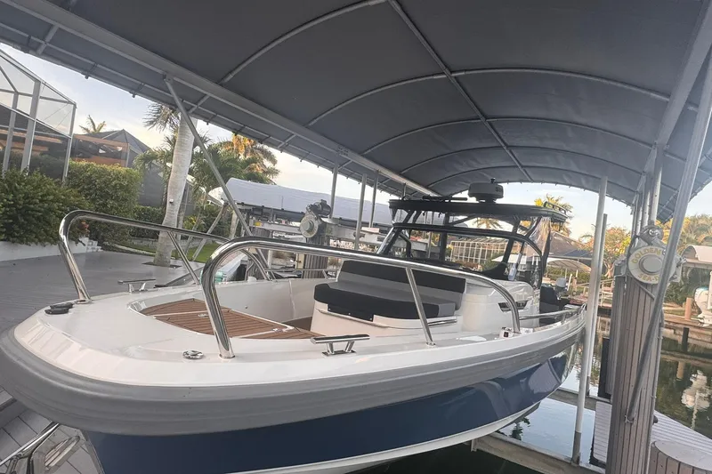 Slide: The Image of 2021 Nimbus T9 boat docked under a canopy, surrounded by tropical greenery. - 2