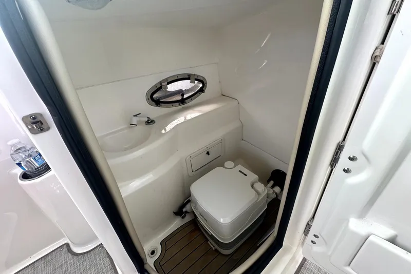 Slide: The Image of 2022 NauticStar 243 DC boat interior with compact bathroom and sink. - 15