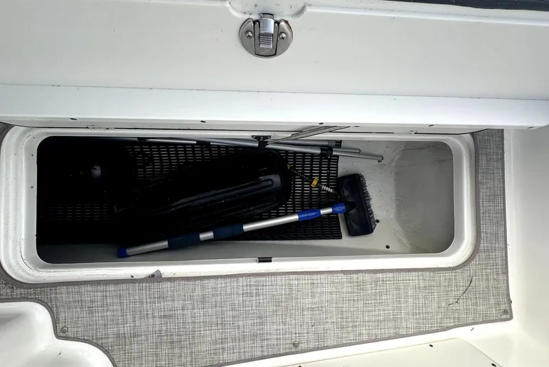 Slide: The Image of Storage compartment of 2022 NauticStar 243 DC boat with cleaning tools inside. - 16