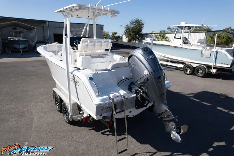 Slide: The Image of 2025 Sea Hunt Ultra 229 boat with outboard motor on trailer in sunny marina. - 17