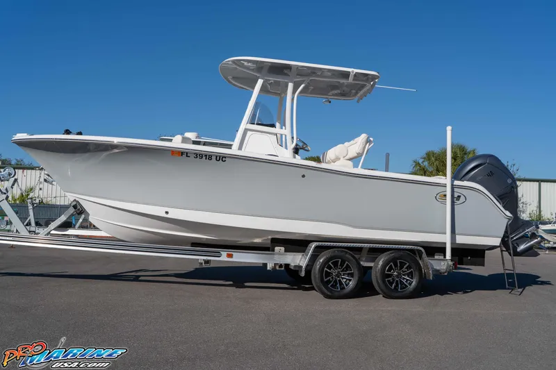 Slide: The Image of 2025 Sea Hunt Ultra 229 boat on trailer, displayed outdoors under clear blue sky. - 20