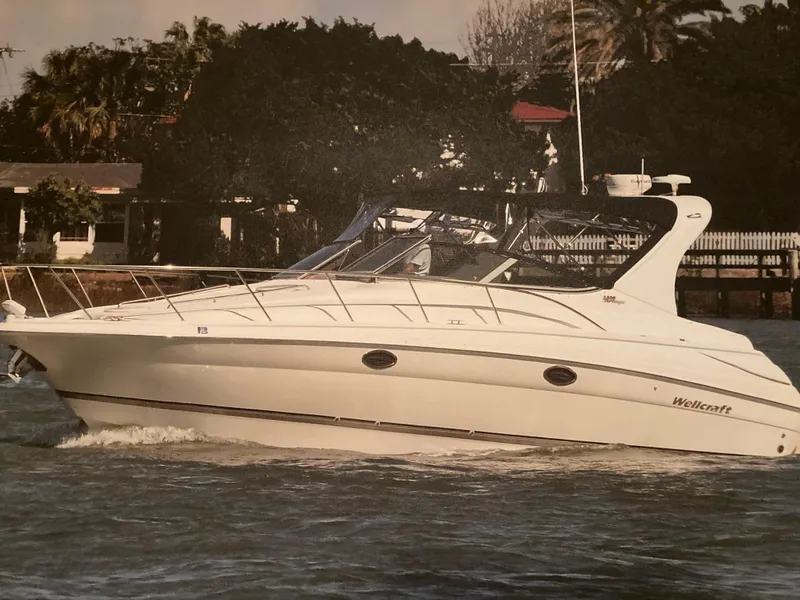 Slide: The Image of 2003 Wellcraft 3300 Martinique cruising on water near a lush shoreline. - 0