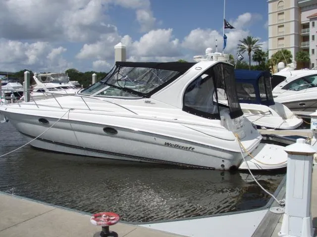 Slide: The Image of 2003 Wellcraft 3300 Martinique boat docked at a marina under a partly cloudy sky. - 1
