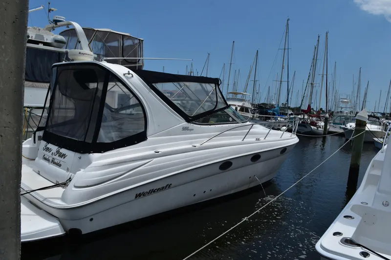 Slide: The Image of 2003 Wellcraft 3300 Martinique yacht docked in a marina with sailboats. - 2