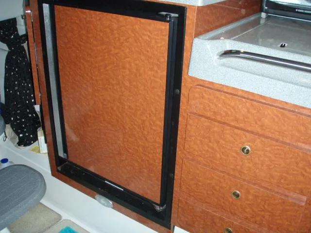 Slide: The Image of 2003 Wellcraft 3300 Martinique interior with wood finish cabinetry and compact fridge. - 22