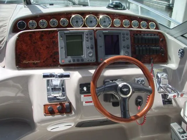 Slide: The Image of 2003 Wellcraft 3300 Martinique dashboard with wood accents and modern navigation controls. - 8