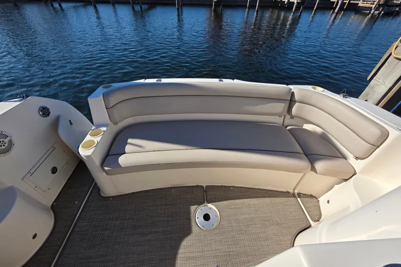 Slide: The Image of 2005 Rinker 300 Express Cruiser boat seating area with beige cushions and cup holders. - 12