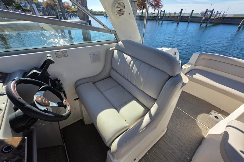 Slide: The Image of 2005 Rinker 300 Express Cruiser interior with helm and seating, docked by the water. - 14