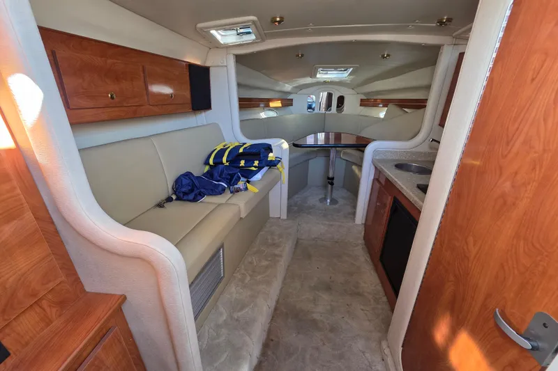 Slide: The Image of 2005 Rinker 300 Express Cruiser interior with seating, table, and kitchenette. - 16