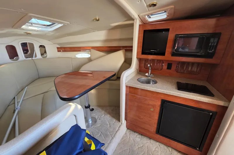 Slide: The Image of 2005 Rinker 300 Express Cruiser interior with kitchenette, seating, and table. - 21