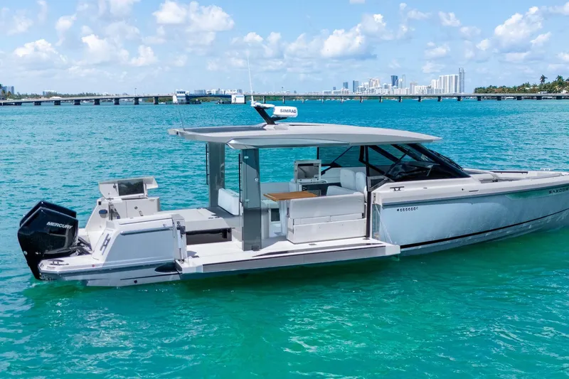 Slide: The Image of 2025 Saxdor 400 GTO luxury motorboat on turquoise water, city skyline in background. - 2