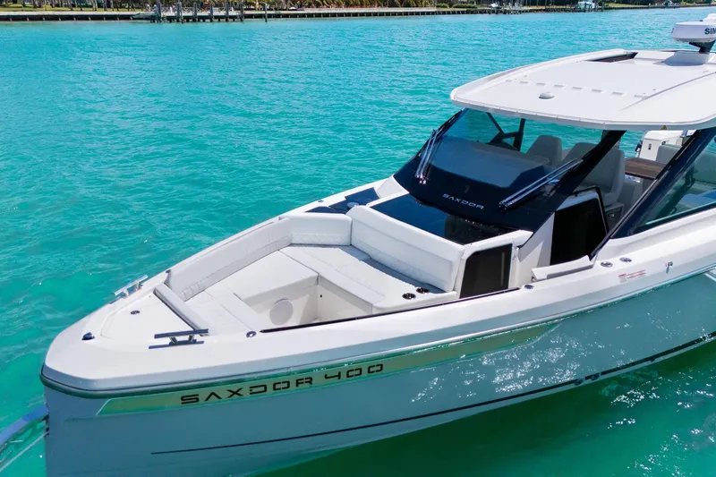 Slide: The Image of 2025 Saxdor 400 GTO luxury boat on turquoise water, showcasing sleek design and spacious deck. - 4