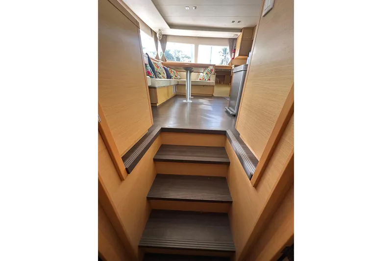 Slide: The Image of Interior view of 2014 Lagoon 450 F yacht, featuring wooden stairs and a cozy seating area. - 11