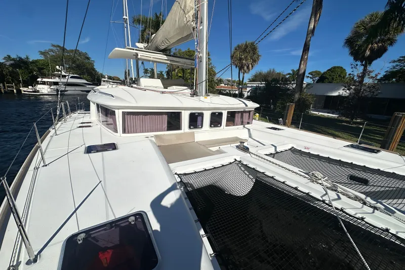 Slide: The Image of 2014 Lagoon 450 F catamaran docked, showcasing spacious deck and sails under clear blue sky. - 52