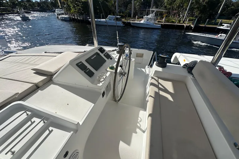 Slide: The Image of Cockpit of 2014 Lagoon 450 F catamaran with steering wheel and seating, docked by a river. - 67