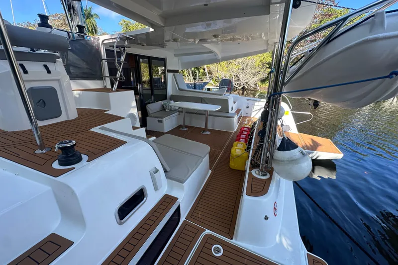 Slide: The Image of 2019 Lagoon 42 catamaran deck with seating, table, and water view. - 12