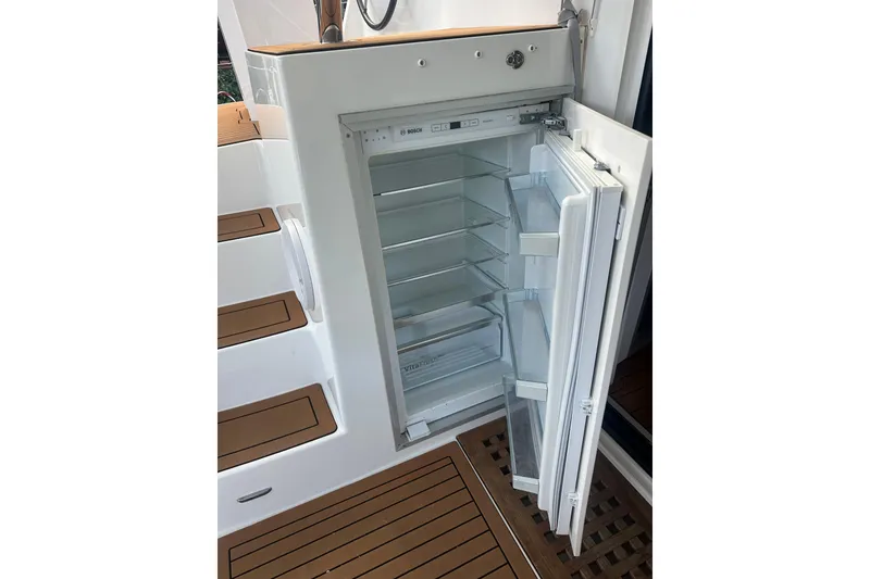 Slide: The Image of Open refrigerator on 2019 Lagoon 42 yacht, showcasing interior shelves and wooden flooring. - 15