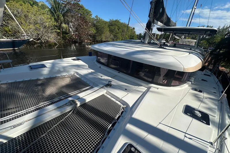 Slide: The Image of 2019 Lagoon 42 catamaran docked by lush greenery and calm waters. - 16
