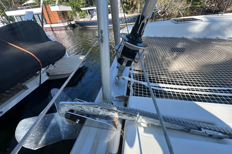 Slide: The Image of 2019 Lagoon 42 catamaran deck with anchor and netting, docked by the water. - 17