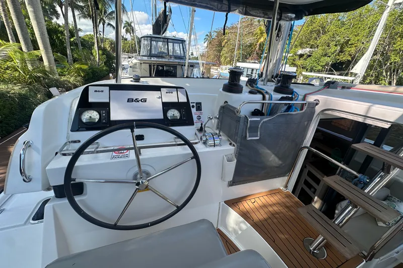 Slide: The Image of Helm of 2019 Lagoon 42 catamaran with B&G navigation system, docked near lush greenery. - 20