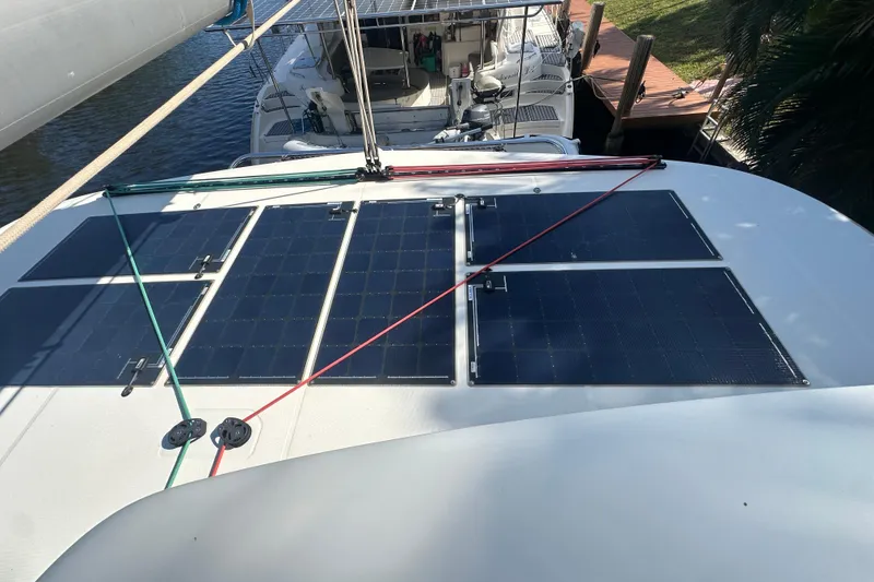 Slide: The Image of 2019 Lagoon 42 catamaran with solar panels on deck, docked near other boats. - 24