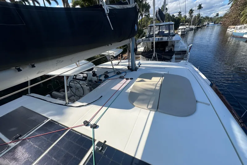 Slide: The Image of 2019 Lagoon 42 catamaran on a serene waterway, featuring solar panels and a spacious deck. - 25