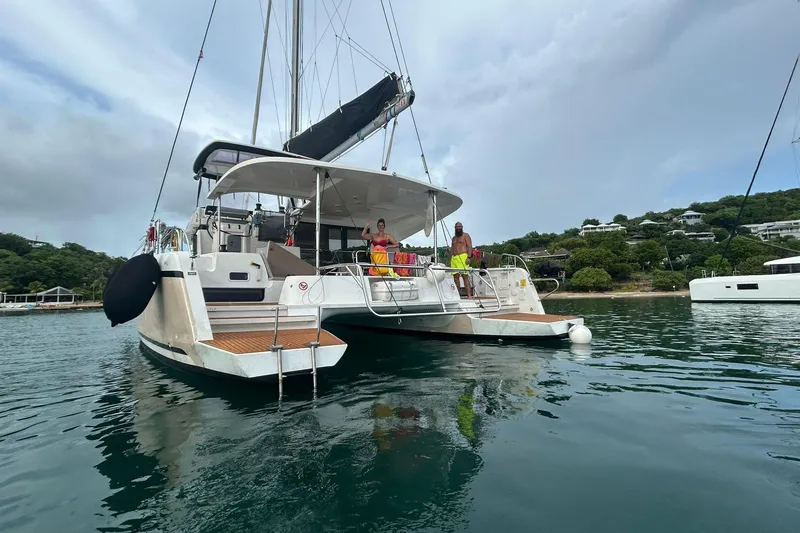 Slide: The Image of 2019 Lagoon 42 catamaran anchored in scenic bay with people on deck. - 5