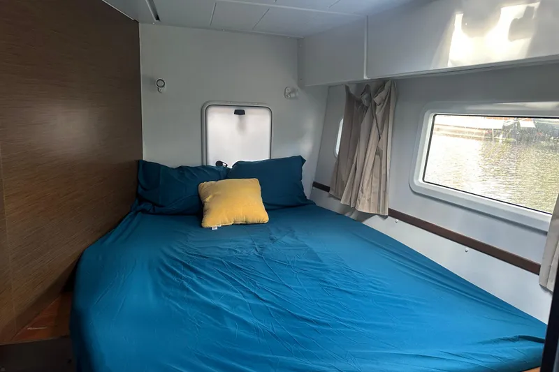 Slide: The Image of Cozy cabin interior of 2019 Lagoon 42 catamaran with blue bedding and window view. - 50