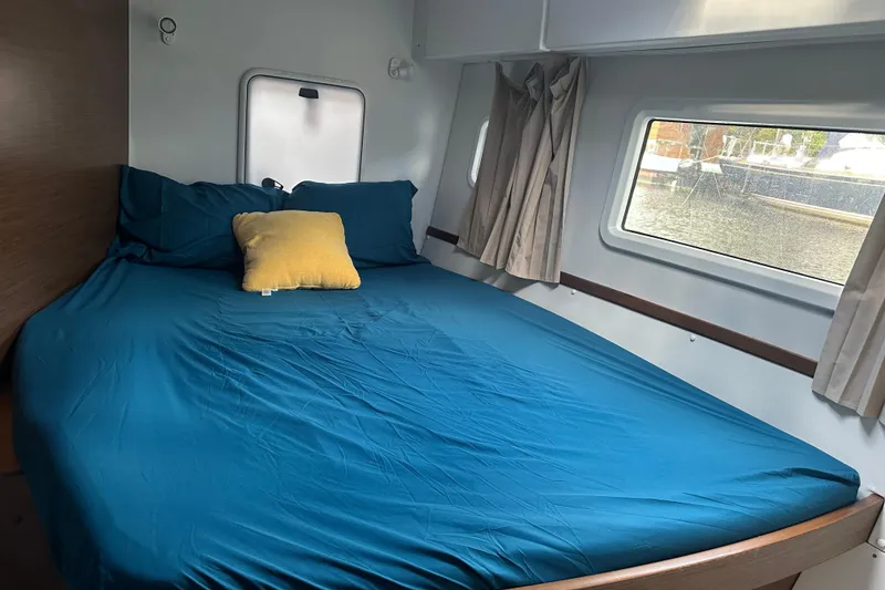 Slide: The Image of Cozy bedroom in 2019 Lagoon 42 catamaran with blue bedding and a yellow pillow. - 51