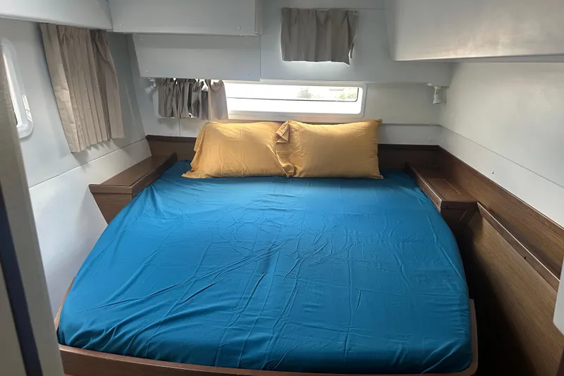 Slide: The Image of Cozy cabin bedroom in 2019 Lagoon 42 catamaran with blue bedding and yellow pillows. - 54