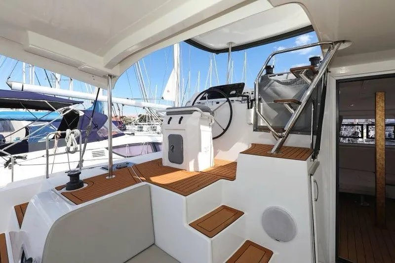 Slide: The Image of 2019 Lagoon 42 catamaran cockpit with helm, wooden steps, and marina view. - 8