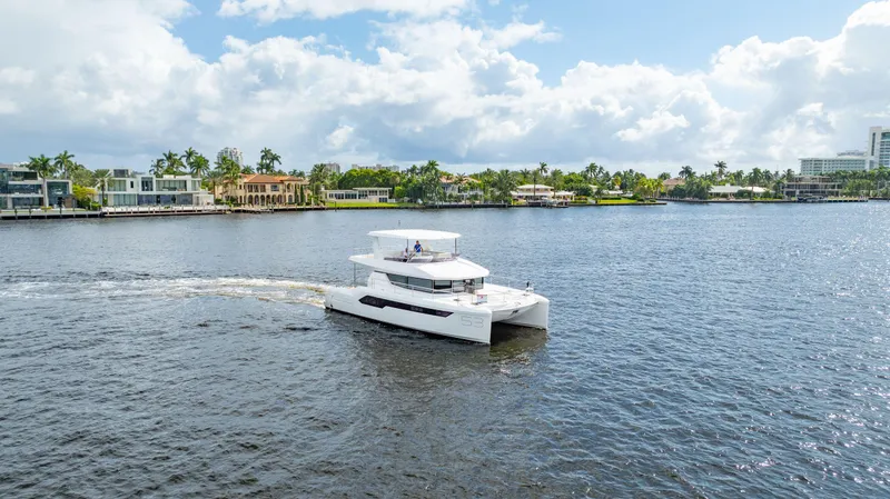 Slide: The Image of 2024 Leopard 53 Powercat cruising on a scenic waterfront with palm trees. - 16