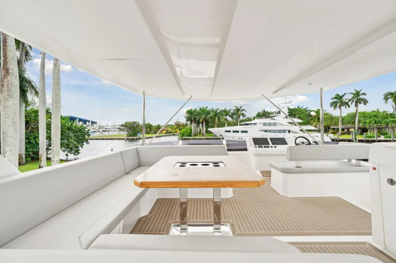 Slide: The Image of 2024 Leopard 53 Powercat yacht deck with seating and table, overlooking marina and palm trees. - 23