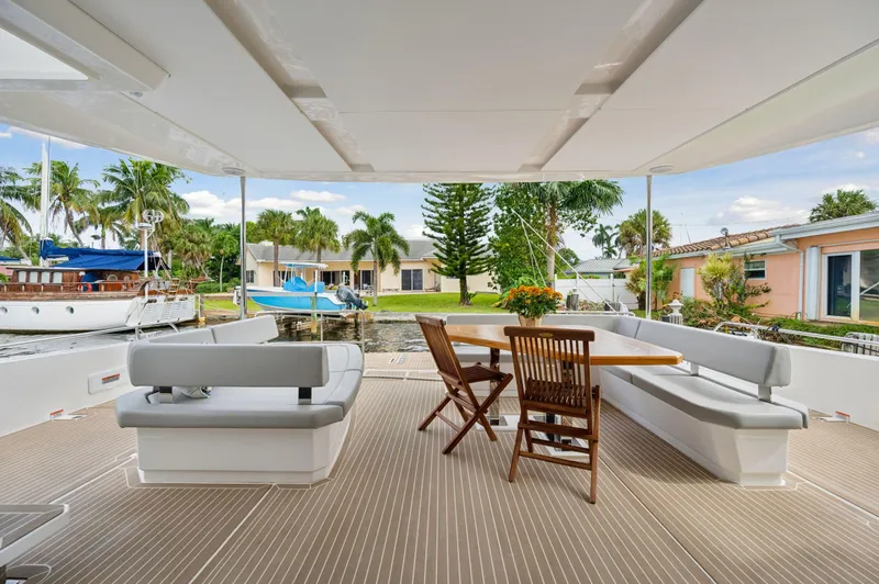 Slide: The Image of Spacious deck of 2024 Leopard 53 Powercat with seating and table, docked by waterfront homes. - 41