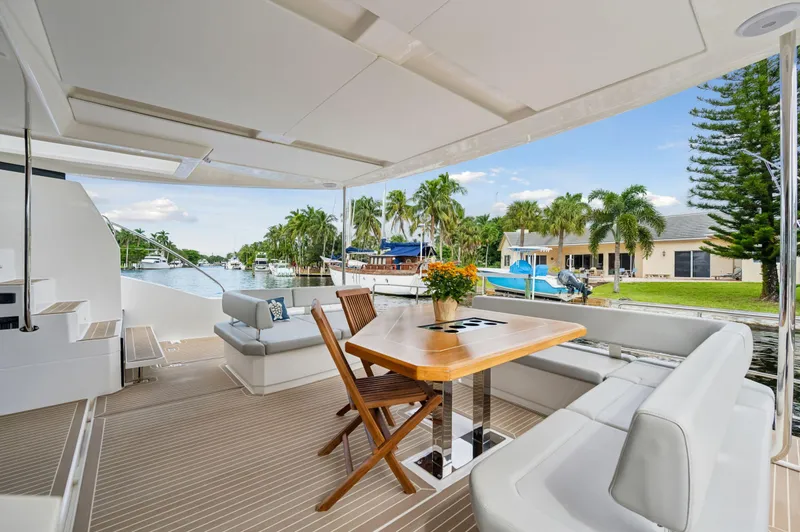 Slide: The Image of Leopard 53 Powercat 2024 yacht deck with seating and table, docked by waterfront homes. - 42