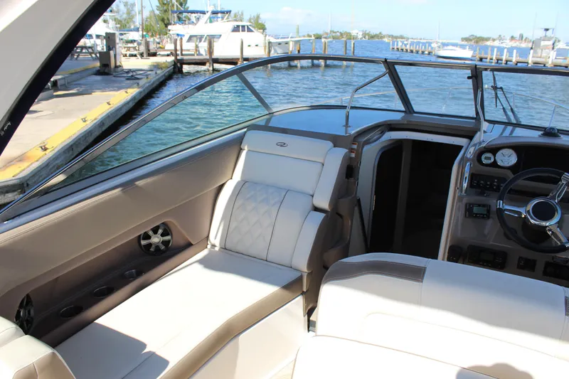 Slide: The Image of 2018 Regal 28 Express boat interior with luxurious seating and dashboard, docked by the water. - 16