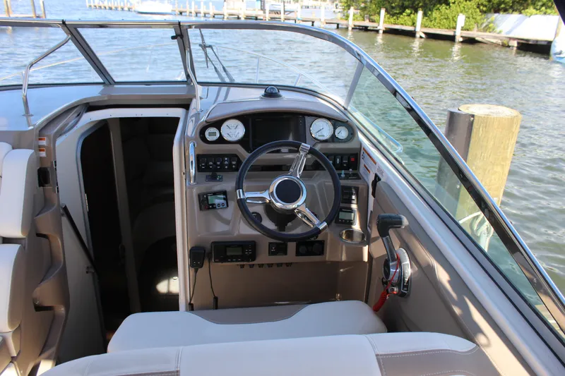 Slide: The Image of 2018 Regal 28 Express boat cockpit with steering wheel and control panel by the water. - 17