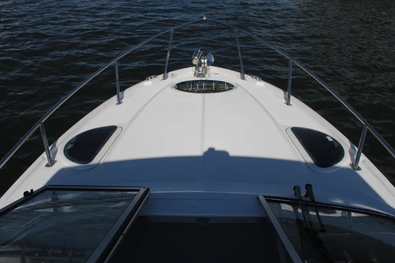 Slide: The Image of 2018 Regal 28 Express boat bow on water, showcasing sleek design and railing. - 25