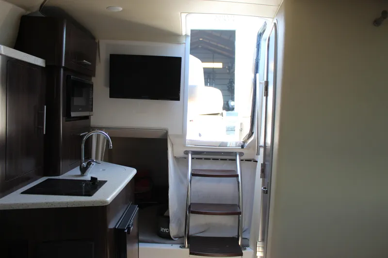 Slide: The Image of 2018 Regal 28 Express interior with kitchenette, TV, and stairs to deck. - 33