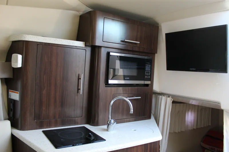 Slide: The Image of 2018 Regal 28 Express boat interior with kitchenette, microwave, and TV. - 34