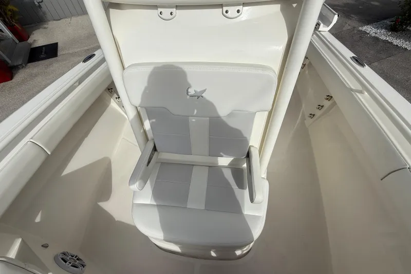 Slide: The Image of 2022 Mako 234 Center Console boat seat with white upholstery and armrests. - 14