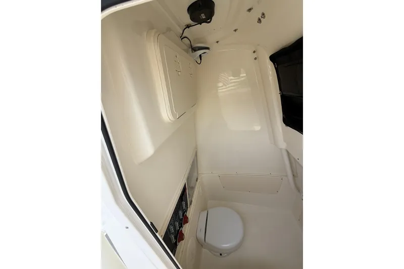 Slide: The Image of Interior of 2022 Mako 234 Center Console boat, featuring a compact marine toilet. - 23