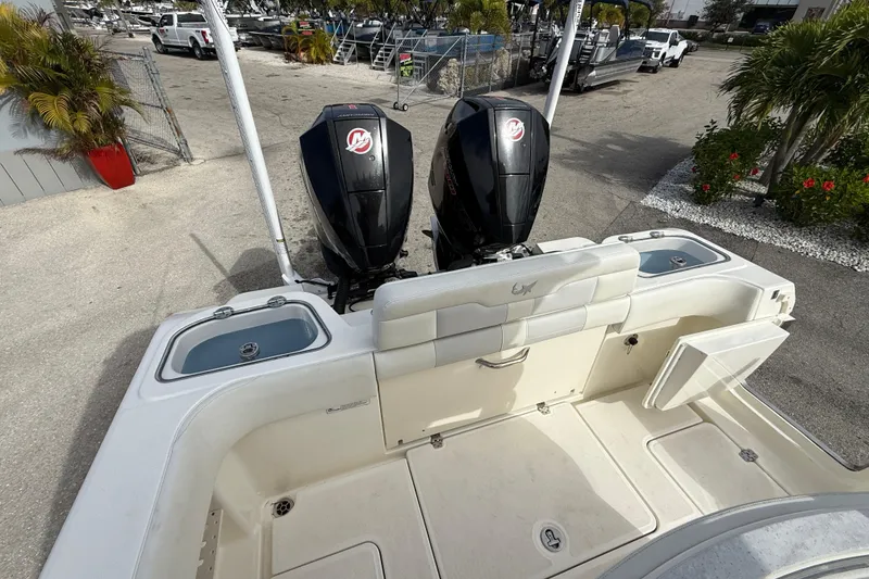 Slide: The Image of 2022 Mako 234 Center Console boat with dual outboard motors, docked outdoors. - 18