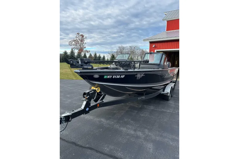 Slide: The Image of 2021 Lund 2175 Pro-V boat on trailer, parked near a red barn. - 3