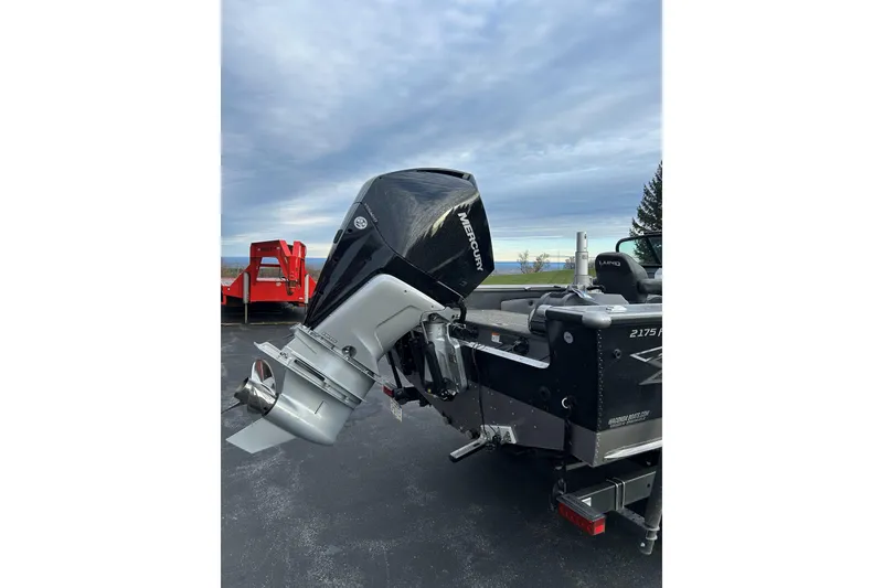 Slide: The Image of 2021 Lund 2175 Pro-V boat with Mercury outboard motor, parked outdoors. - 6