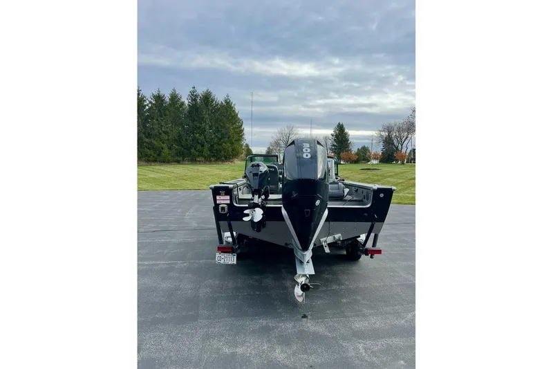 Slide: The Image of 2021 Lund 2175 Pro-V boat with powerful outboard motor on a paved surface. - 7