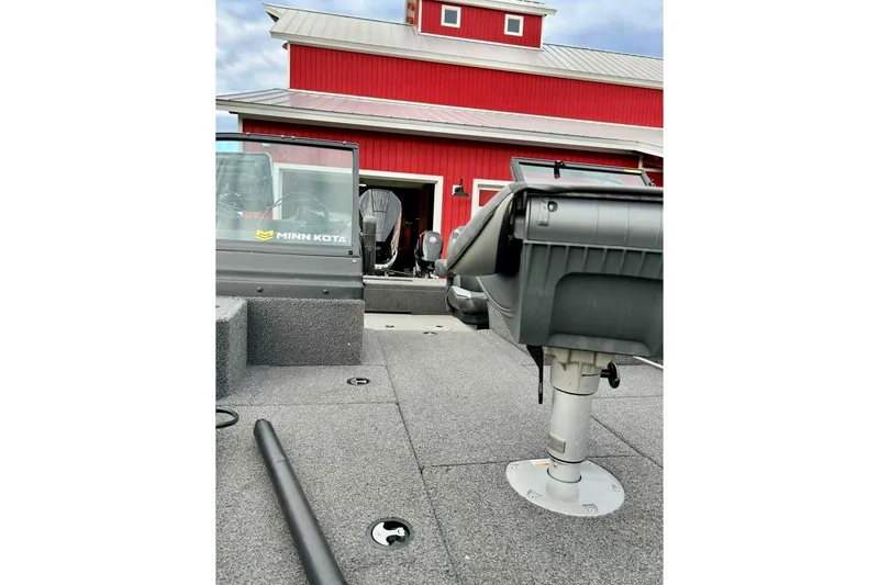 Slide: The Image of 2021 Lund 2175 Pro-V boat with Minn Kota equipment, parked near a red building. - 8