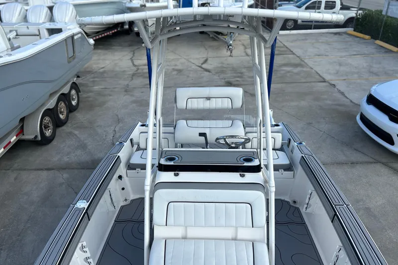 Slide: The Image of 2019 Yamaha Boats 190 FSH Sport interior with seating and steering wheel, parked outdoors. - 21