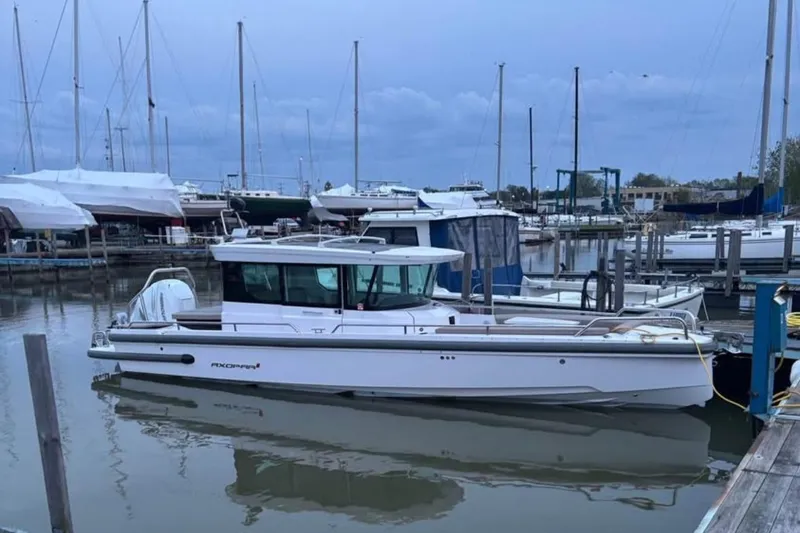 The Image of 2022 Axopar 28 CABIN boat docked in a marina with sailboats. - 0