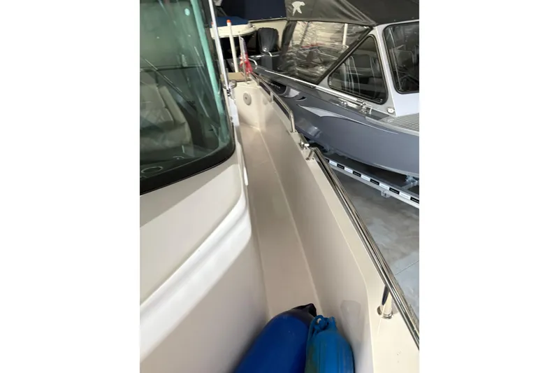 Slide: The Image of 2022 Axopar 28 CABIN boat side view in storage, featuring sleek design and blue fenders. - 14